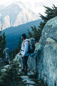 背包客伫立山巅，远眺雪峰与苍翠林海