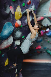 女子奋力攀爬室内岩壁，专注挑战极限