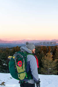 雪地旅人背负重装远眺暮色群山