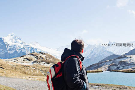 背包客凝望雪山湖泊的壮丽风景