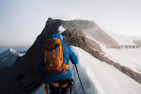 攀登者背影朝向云雾缭绕的雪峰顶
