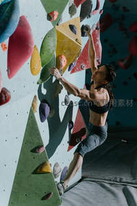 女攀岩者飞身抓握彩色岩点