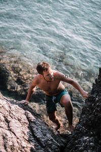 男子攀爬海岸礁石，挑战自然极限