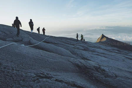 登山者征服险峻山巅，云海之上挑战极限