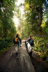 森林小径上两人携装备迎光而行