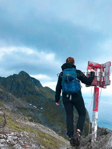 山巅路标旁，徒步者回望苍茫山脉与大海