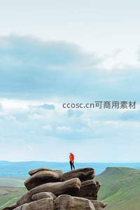 橙衣旅人伫立巨石之巅