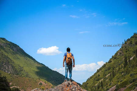 背包客伫立山巅，远眺青翠山谷与蓝天白云