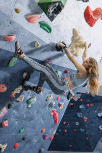 从上方视角看女子在倾斜岩壁上奋力攀爬