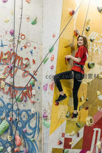 红衣女孩在黄色岩壁上微笑攀登