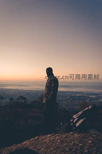 晨曦山巅，孤独身影俯瞰薄雾笼罩的山谷