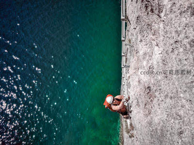 攀岩者俯瞰碧绿海面挑战垂直峭壁