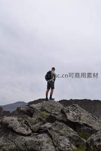 孤影登高，背包客静立云雾缭绕的岩顶