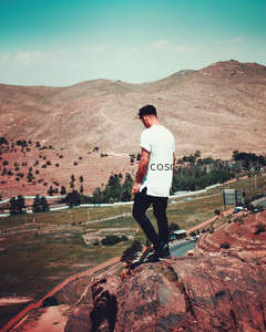 青年立崖边俯瞰山谷，感受大地辽阔