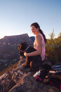 山顶日落时分，女孩与爱犬共享宁静时光
