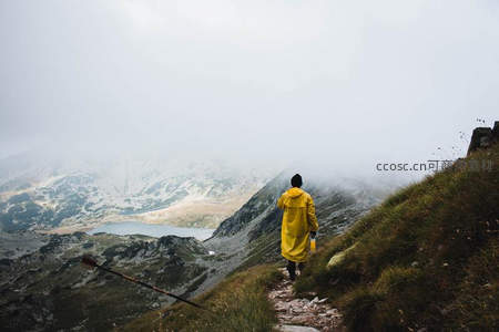 雨中徒步者穿行雾锁山峦间