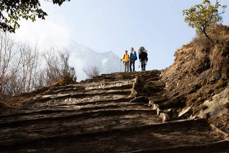 三人结伴攀登石阶仰望雪山