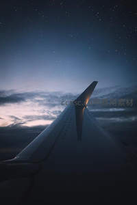 夜空繁星下，飞机机翼剪影划过云层边缘