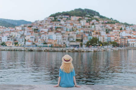 女孩静坐水边眺望山城小镇