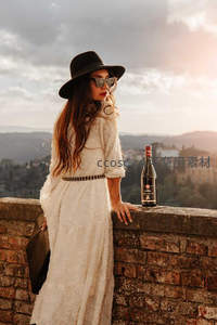 女子倚墙品酒远眺山谷风光