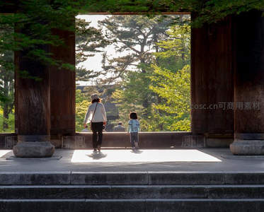 母子携手穿过古寺门廊望向绿意