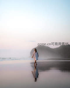 晨雾中白衣女子独行湿润沙滩