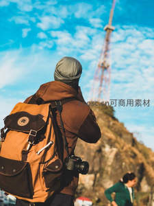 背包客手持相机拍摄山顶铁塔