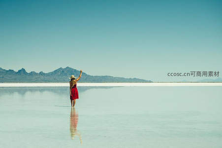 红裙女子立于镜面盐湖，远山如黛