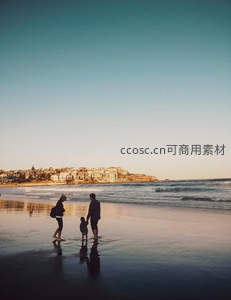 夕阳海滩上的一家三口漫步剪影