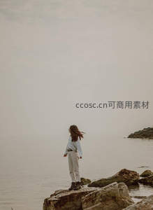 女子独自伫立海边礁石之上