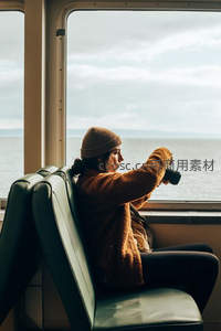 女子船舱内持相机凝望海景