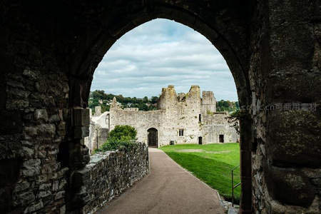 石拱门内窥古堡，废墟庭院绿草如茵