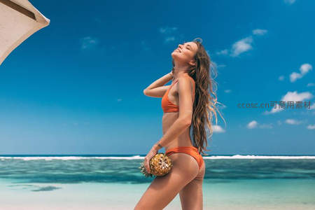 比基尼美女海边享受阳光，手捧菠萝笑容灿烂