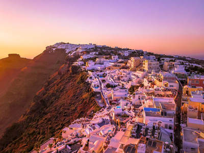 粉紫霞光映衬圣托里尼，白墙屋舍如童话世界