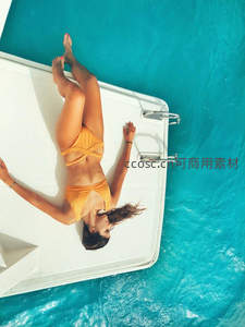 橙色比基尼女子躺游艇甲板晒日光浴