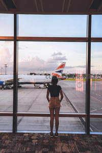 机场守望：少女伫立窗前凝视停机坪上的英航客机