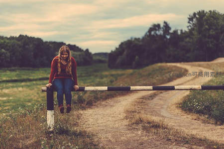 女孩坐乡间栅栏眺望远方田野