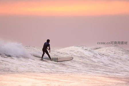 夕阳冲浪者驾驭海浪的剪影瞬间