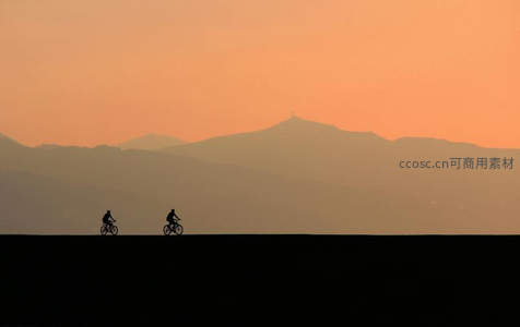 暮色山峦前双人骑行剪影如画