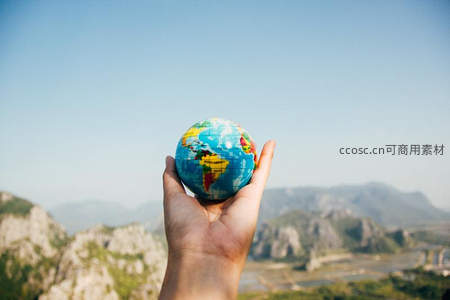 手掌托举地球仪，远眺群山如画风景