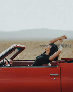 红车敞篷中女子舒展双臂，享受旷野自由