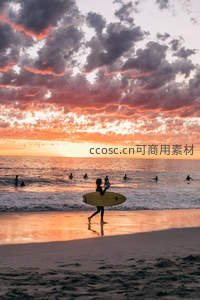 夕阳海滩冲浪者，剪影踏浪归岸时