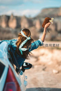 女孩车窗探身手捧雏菊远眺