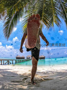 沙滩上踢起细沙，海岛度假瞬间