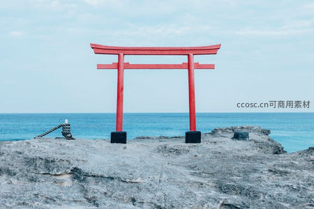 海边岩石上的红色鸟居，背景是蔚蓝大海
