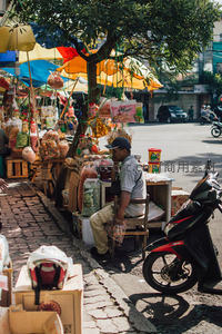 街边小贩在树荫下守候五彩摊位