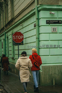 绿墙街角的行人与STOP标志