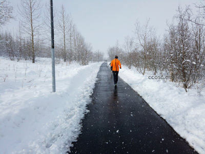 雪中漫步，橙衣行者踏雪归途
