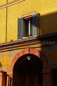 暖阳洒落黄色外墙，窗台红花点缀拱门古韵