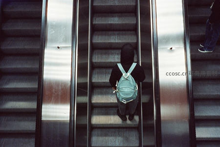 背影少年乘扶梯穿梭都市空间